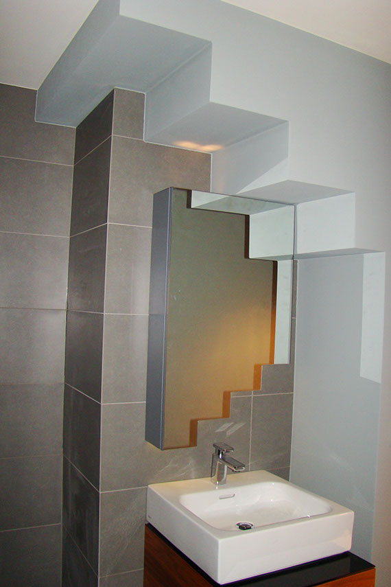 Zbliżenie na lustro wkomponowane w schody, które tworzą w łazience sufit